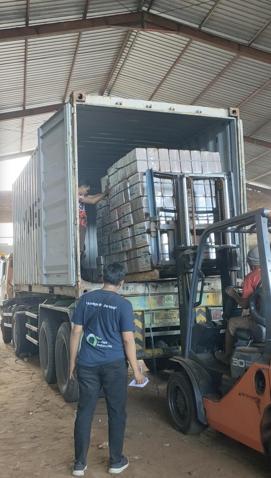 Forklift loading a pallet of cocopeat blocks into a container